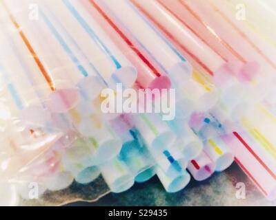 Overexposed photo of bright, striped, multi colored plastic straws in bag, as seen from bottom end Stock Photo