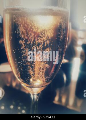 Champagne or sparkling wine bubbles rising in a freshly poured glass standing on a table waiting to be drunk Stock Photo