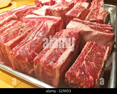 Seasoned raw beef short ribs on a baking pan ready to put into the oven. Stock Photo