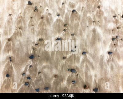 Pebbles and wind blown sand patterns on a Welsh beach. Stock Photo