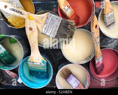 Paint pots and brushes at an artist’s studio. Stock Photo