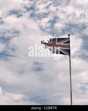 Rippped and torn Union Jack flag flying in the wind Stock Photo