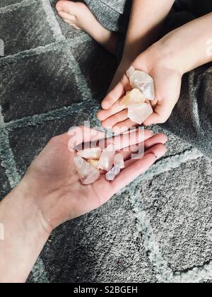 Mother and son holding colorful gem stone crystal quarts rocks in their hands - while sitting on a checkered pattern blue and gray rug Stock Photo