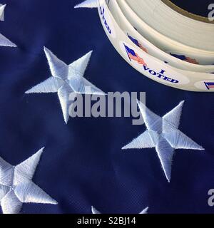 Roll of I voted stickers on corner of part of American flag, Stars and Stripes Stock Photo