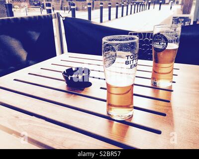 Half drunk pints of beer left on a table in a beer garden. Stock Photo