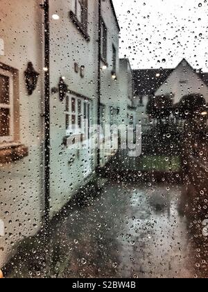 Looking out of the window in the pouring rain, with raindrops on the window pane. Stock Photo