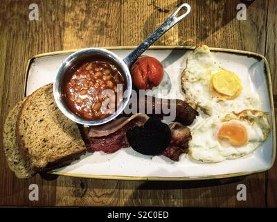 All day full English breakfast meal on a wooden table top. Stock Photo