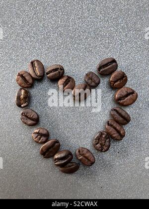 Fresh coffee beans arranged in a heart shape on a taupe background Stock Photo