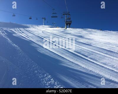 Winter landscape on the beautiful sunny day on the mountain with ski lift above the snowy ski piste. Stock Photo