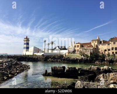 The lighthouse ‚Farol de Santa Marta‘ and the ‚Casa de Santa Maria‘ in the coastal city Cascais, Portugal. Stock Photo