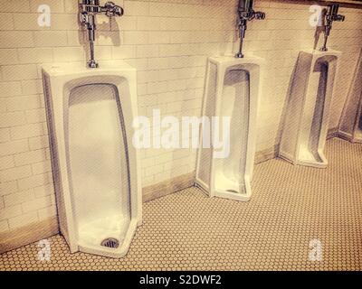 Old fashion full length urinals in  a  men’s room, USA Stock Photo