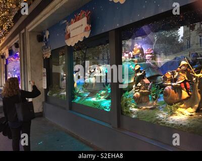 Woman taking photo of Christmas window at Printemps department store, Paris, France Stock Photo