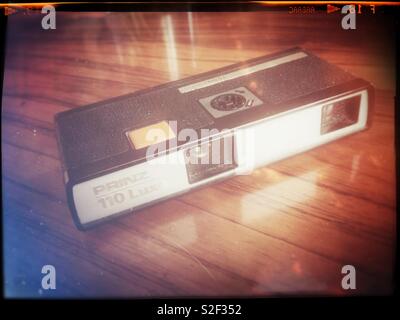 A vintage pocket camera from ca 1972 in the redundant 110 film format on a mahogany table. Retro treatment.