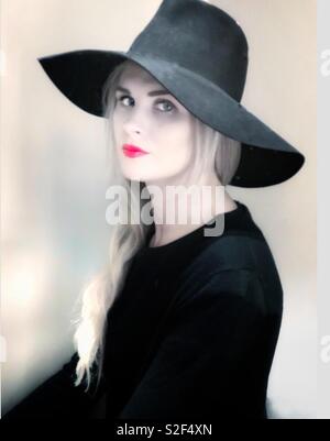 A young blonde woman dressed in black gazed at the camera. Stock Photo