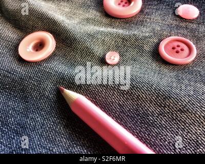 Pink buttons and pencil on denim Stock Photo