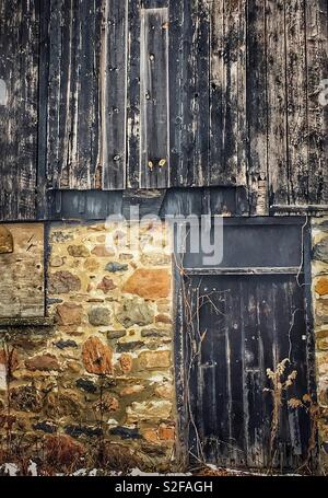 Close up of textured & weathered wood barn with field stone foundation. Background, pattern, texture, rustic feeling. Stock Photo
