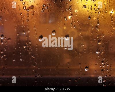 View through a rainy train window at night to the platform. Stock Photo