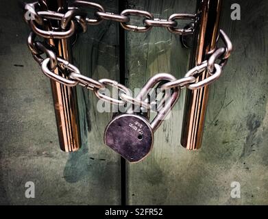 Security provided by padlock and chain on the door handle. Stock Photo