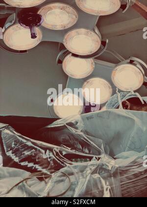 Operating lights in an operating theatre with surgeon’s head and theatre cap visible. Stock Photo