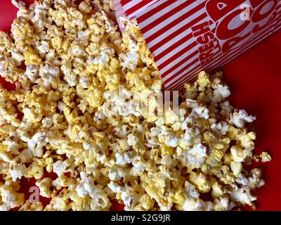 Spilled bag of popcorn on a red surface Stock Photo