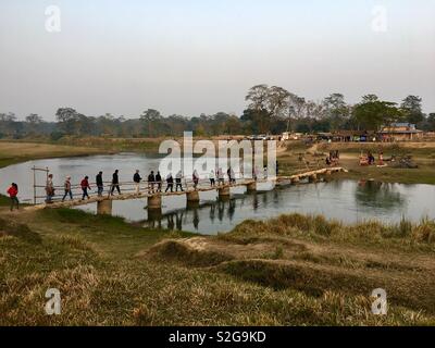 Visitors crossing footbridge across Narayani river to the elephant breeding and training center at Chitwan national park, Nepal. Stock Photo