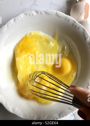 Whisking eggs in a white bowl Stock Photo