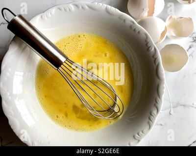 Whisked eggs in a white bowl Stock Photo