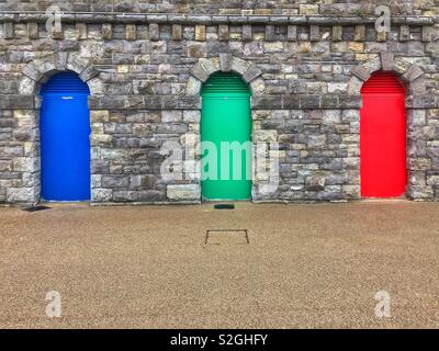 Three coloured doors in a wall at Barry Island, South Wales. Stock Photo