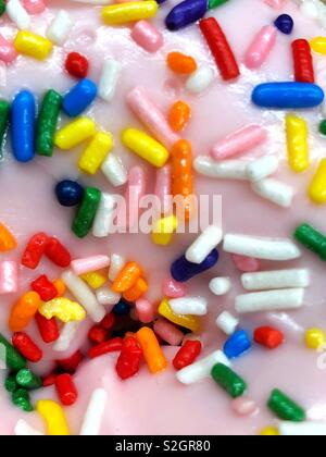 colorful rainbow of sprinkles on pink glazed doughnut Stock Photo