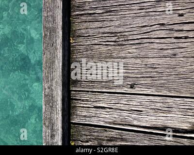 old jetty peir wood close up with clear turquoise sea water in background Stock Photo