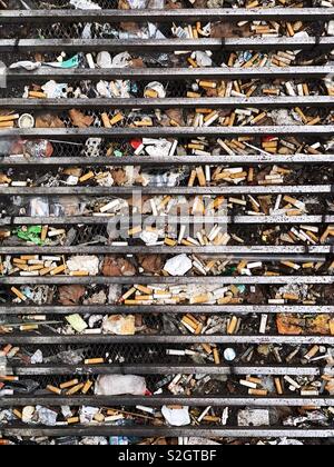 Urban litter and cigarette butts in street grille, London, UK Stock Photo