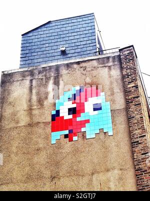 A pixelated tile pac-man image by the French street artist, Invader, on the side of a building in London, England Stock Photo