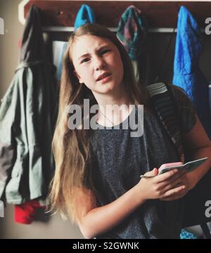 Candid portrait of grumpy teen girl holding smartphone Stock Photo