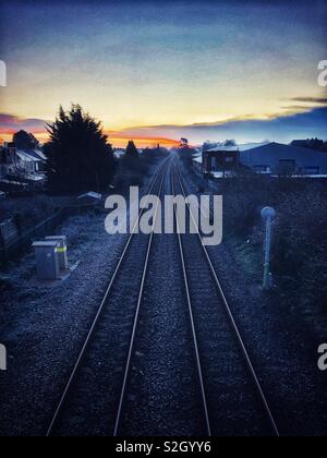 Train tracks leading into the sunrise on a frosty January morning. Stock Photo