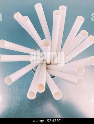 Close up looking down at paper straws in a glass container on stainless surface. Stock Photo