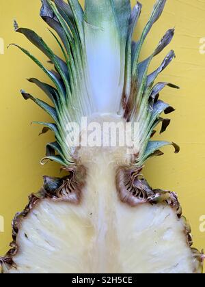 Fresh pineapple sliced in half on yellow background Stock Photo