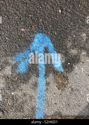 Blue arrow spray painted on the ground Stock Photo