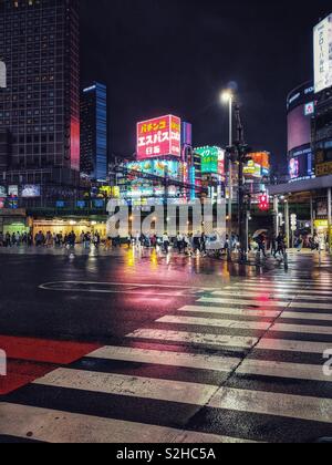 Pedestrians at night in Shinjuku district of Tokyo, Japan Stock Photo