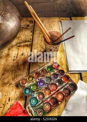 Painter’s working place, paints, brushes and paper on wooden table Stock Photo