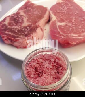 Still life of two raw ribeye steaks and jar of special seasoning salt, USA Stock Photo