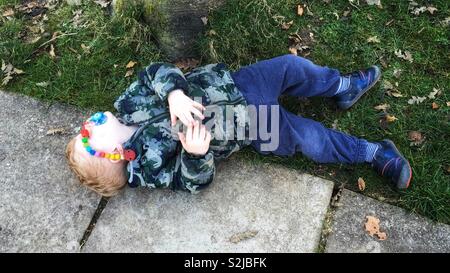 Exhausted two year old boy sleeping on the ground. Stock Photo