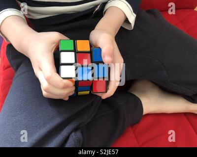 Small child playing with Rubik’s cube Stock Photo