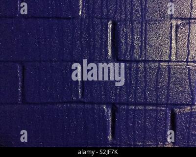 A full frame, brick wall background that is painted deep blue and covered in condensation that is dripping down the wall Stock Photo