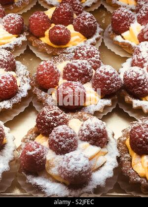 Professionally prepared mouth watering delicious raspberry tarts with an orange cream and powdered sugar. Stock Photo