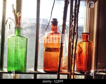 Sunlit Victorian medicine bottles on a window shelf in the Old Operating Theatre museum, London, England, UK. Stock Photo