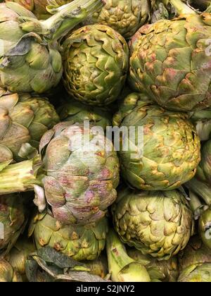 Fresh artichoke heads on display and ready for sale at the local produce vendor. Stock Photo