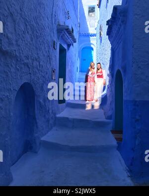 Two woman standing on steps in alley way in blue city, chefchaouen, Morocco, africa Stock Photo