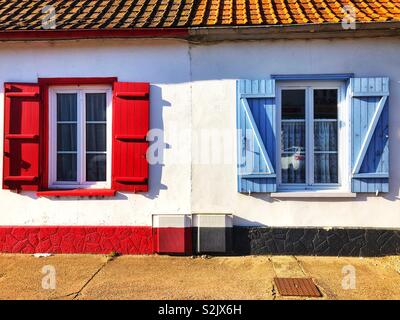 Two windows with red and blue shutters, France. Stock Photo