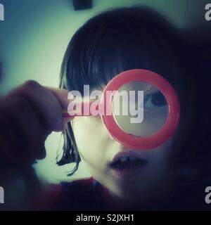 Little Girl Looking Through A Toy Magnifying Glass Stock Photo