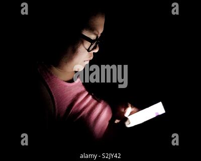 Lady using her smartphone in the dark. Stock Photo